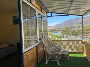 a balcony with two chairs and a view of a river at Neryok's Indus view in Chimre