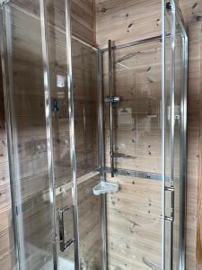 een douche in een kamer met een houten muur bij Bromlebu in Notodden