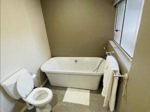 a bathroom with a white tub and a toilet at Grace Gardens - Grace in Pretoria