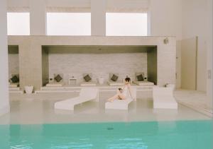 a woman sitting on the edge of a swimming pool at Grand Richmond Stylish Convention Hotel in Nonthaburi