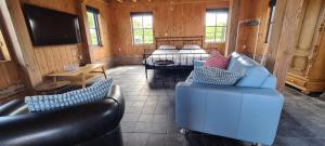 a living room with two blue couches and a television at Den Hooimijt in Kats