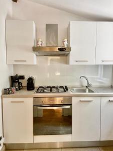 a kitchen with white cabinets and a stove and a sink at Green Escape Guesthouse with Pool in Villa in Florence