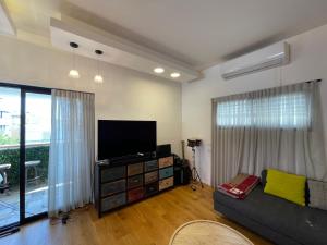 ein Wohnzimmer mit einem Sofa und einem Flachbild-TV in der Unterkunft Bograshov Rooftop Apartment in Tel Aviv