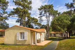 a row of cottages in a park with trees at Azureva Ile d'Oleron in Grand-Village-Plage