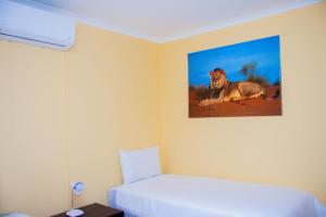 1 dormitorio con 1 cama y una foto de un león en la pared en Home@Amalia’s en Rundu