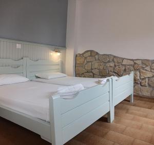 Habitación con 2 camas blancas y pared de piedra. en Elia en Skála