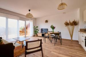 cocina y sala de estar con mesa y sillas en Le Noyer - Appt avec terrasse et jardin partagé, en Puberg