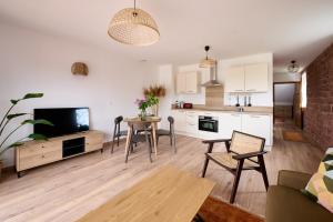 a living room with a table and a kitchen at Le Noyer - Appt avec terrasse et jardin partagé in Puberg