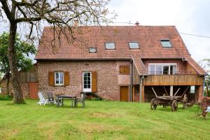 a brick house with a table and chairs in the yard at Le Noyer - Appt avec terrasse et jardin partagé in Puberg