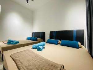 2 łóżka w pokoju z niebieskimi poduszkami w obiekcie Proboscis Guest House w mieście Sandakan