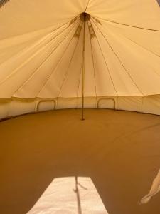 Unfurnished Bell Tent close to SWC path في هارتلاند: خيمة بيضاء كبيرة مع ظل على الأرض