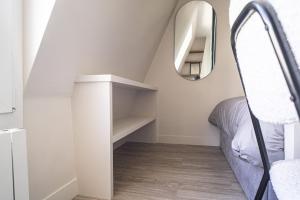 ein kleines Schlafzimmer im Dachgeschoss mit einem Bett und einem Spiegel in der Unterkunft Bright 20m near the Eiffel Tower in Paris