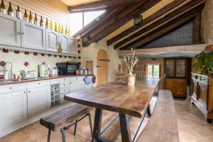 eine große Küche mit einem Holztisch und Bänken in der Unterkunft Gîte Divin - Belle maison champêtre in Doué-la-Fontaine