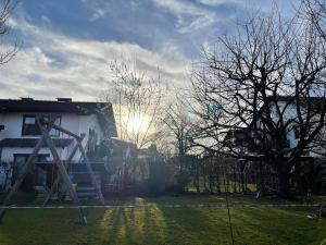 uma casa com o sol brilhando atrás de uma árvore em Gartenhäuschen im Grünen em Bad Aibling