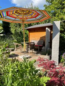un patio con sombrilla, mesa y sillas en Gartenhäuschen im Grünen, en Bad Aibling