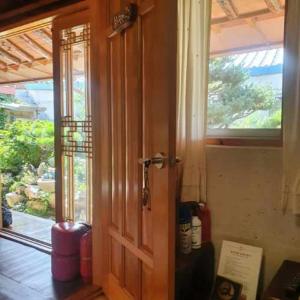 Una puerta de madera en una habitación con ventana en Beautiful Garden Fine Day House, en Jeonju
