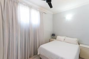 a white bedroom with a bed and a window at Boulder Bay 9 in Ballito
