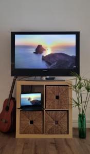Unique Sea & City Lifestyle Studio في ليماسول: تلفزيون بشاشة مسطحة جالس على منصة فيها غيتار