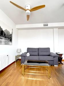 uma sala de estar com um sofá azul e uma ventoinha de tecto em La Casa de Mansilla em Mansilla de las Mulas