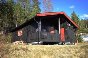a black house with a red roof on a hill at Halvorseth in Prestfoss