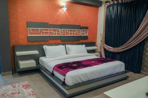 a bedroom with a large bed with a red wall at The Luxus Lodge in Islamabad