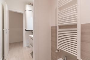 uma casa de banho com paredes brancas, um lavatório e um espelho. em Palazzetto La Quadra di San Faustino - F&L Apartment em Brescia