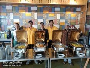 a group of people standing behind a table with food at Hotel Highway Inn Andheri East in Mumbai