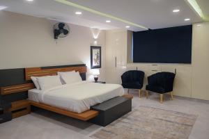 sypialnia z łóżkiem, 2 krzesłami i telewizorem w obiekcie The Luxus Lodge w mieście Islamabad