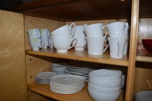 a shelf with white dishes and cups and plates at Appartement-terrasse parking privé Meublé de Tourisme 4 étoiles in Belfort