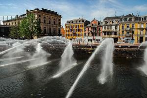 a group of water fountains in a city with buildings at Appartement-terrasse parking privé Meublé de Tourisme 4 étoiles in Belfort