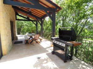a patio with a grill and a table and chairs at Magnifique Villa de prestige, piscine chauffée in Marnac