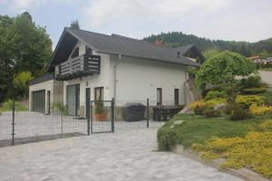 une maison blanche avec un toit noir et une clôture dans l'établissement Domek nad Żylicą, à Szczyrk