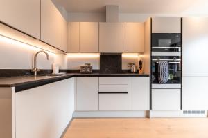 a kitchen with white cabinets and black counter tops at Apartment Fourteen Staines Upon Thames - Free Parking - Heathrow - Thorpe Park in Staines