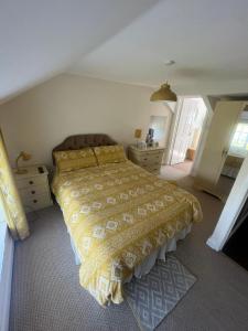 a bedroom with a bed with a yellow bedspread at Broadmoor Farm in Kilgetty