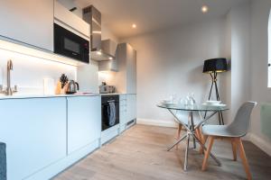 - une cuisine avec une table, une petite table et des chaises dans l'établissement Apartment Thirty One Staines Upon Thames - Free Parking - Heathrow - Thorpe Park, à Staines