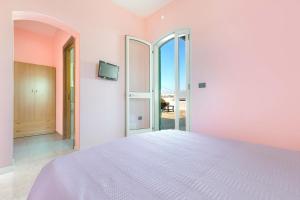 a bedroom with a large bed with pink walls at Dima Apartments by BarbarHouse in San Foca