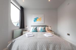 um quarto branco com uma cama grande e 2 almofadas em Apartment Thirty Two Staines Upon Thames - Free Parking - Heathrow - Thorpe Park em Staines