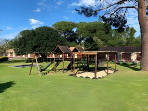 un parque infantil con columpio en un patio en Sunny 2 bedroom apartment on stunning golf course, en Plettenberg Bay