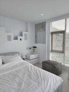 a white bedroom with a large bed and a chair at White window sea in Hengchun