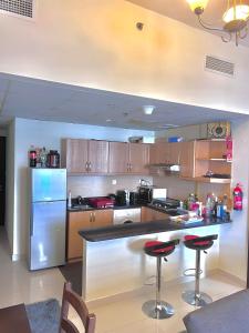 a kitchen with a refrigerator and a counter with stools at Dubai Sport City in Dubai