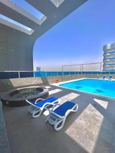a swimming pool with two lounge chairs next to a swimming pool at Dubai Sport City in Dubai