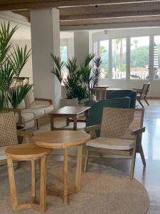 a lobby with tables and chairs and plants at Aparthotel HG Jardin de Menorca in Son Bou
