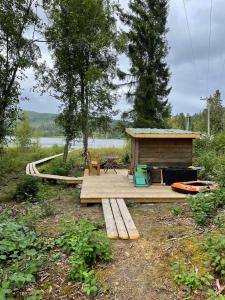 una terraza de madera con una cabaña junto a un lago en Village Cottage In The High Coast Area 