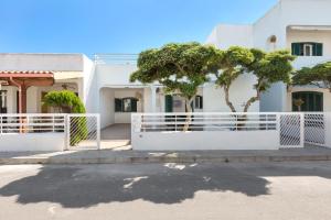 a white fence in front of a house with a tree at Dima Apartments by BarbarHouse in San Foca