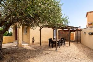 een patio met een tafel en stoelen onder een luifel bij La Villa d'Isa et Seb in Narbonne