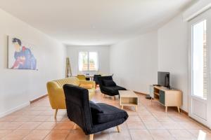 un salon avec des chaises jaunes et noires et une télévision dans l'établissement La Villa d'Isa et Seb, à Narbonne