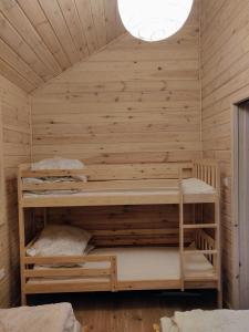 a room with two bunk beds in a wooden wall at Kujanki - domki z widokiem na jezioro in Zakrzewo