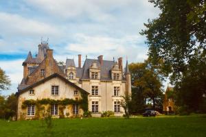 una casa grande con techo en un campo verde en Cottage du château, en Erbrée