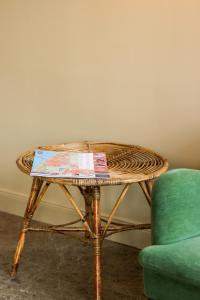 einen Korbtisch neben einem grünen Stuhl und einem Tisch in der Unterkunft Mimosa Hotel in Westerland
