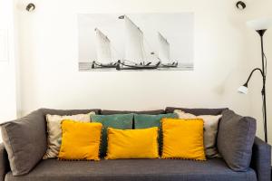 uma sala de estar com um sofá com almofadas amarelas em Blue Salinas em Aveiro